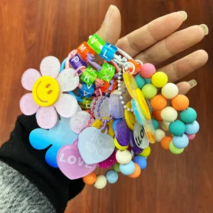Nahaufnahme von bunten Sonnenblumen- und Herz-Anhängern mit Perlen, in der Hand gehalten.