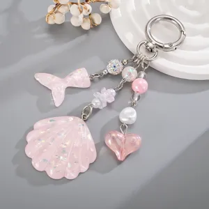 Détail du pendentif coquillage et queue de sirène en acrylique rose pailleté pour sacs.