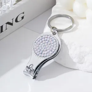 Macro close-up of a silver rhinestone-studded nail clipper keychain and bottle opener