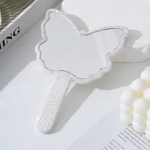 Dettaglio dello specchio a mano a forma di farfalla decorato con strass lucidi