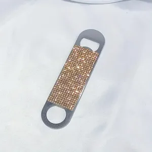 Close-up of a portable stainless steel bottle opener encrusted with sparkly gold rhinestones.
