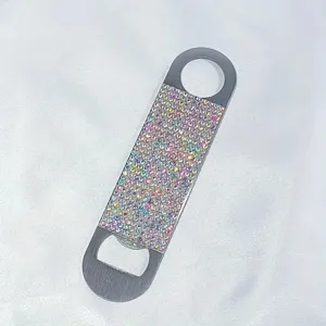 Detailed view of a portable rhinestone-encrusted beer bottle opener on white silk.
