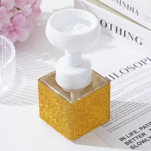 Close-up of luxury gold rhinestone foaming bottle with white flower pump head