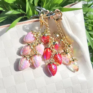 Detailed view of glossy colorful resin strawberry charms attached to a white woven bag