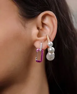 Detailed view of model wearing fuchsia carabiner earring and elegant white pearl studs