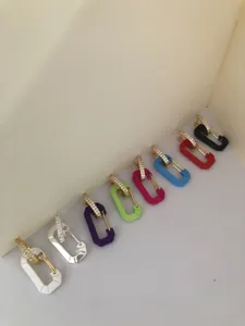 Detailed view of colorful safety pin earrings with pavé stones in various vibrant hues.