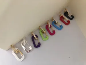 Close-up of colorful safety pin earrings with rhinestone pavé studs in nine shades