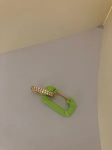 Detail of neon green carabiner earring with micro-pave crystals and gold accents.