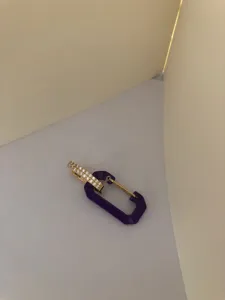 Detailed view of a trendy purple carabiner earring with gold-toned pavé cubic zirconia
