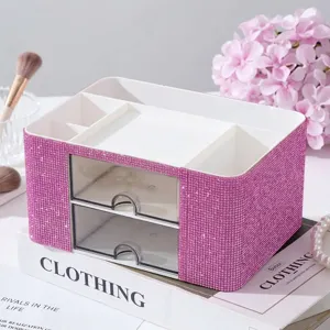 Close-up of pink rhinestone makeup organizer with two clear drawers on a desk.