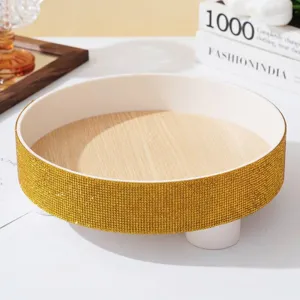 Detail of a luxury round tray with golden rhinestones and wood grain texture base.