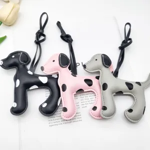 Dettaglio di tre ciondoli per borse a forma di dalmata in pelle colorata con cordini