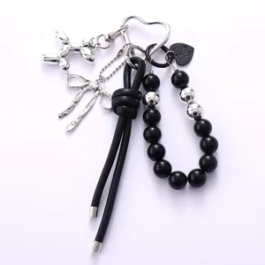 Close-up of black leather cord keychain with acrylic beads and silver balloon dog charm.