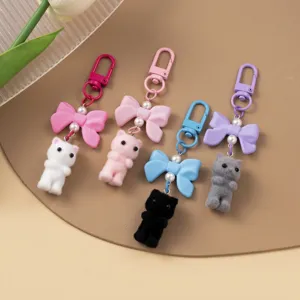 Detail view of cute flocked cat keychains with colorful resin bows and bag charms
