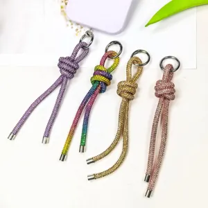 Detailansicht von vier bunten geknoteten Handy-Lanyards und Taschenanhängern mit Strasssteinen