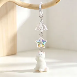 Detail of a cute white flocked cat keychain with an iridescent star and clear bell charm