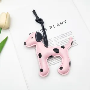 Dettaglio di un ciondolo per borsa in pelle dalmata rosa con macchie nere e cinturino.