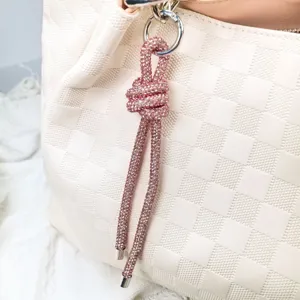Detailansicht eines funkelnden pinkfarbenen Strass-Knotenanhängers an einer Tasche