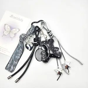Detailed view of a handmade black leather bear keychain with shiny silver charms.
