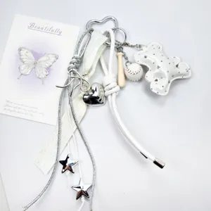 Detail view of white leather bear, baseball bat, and silver heart charms on a keychain