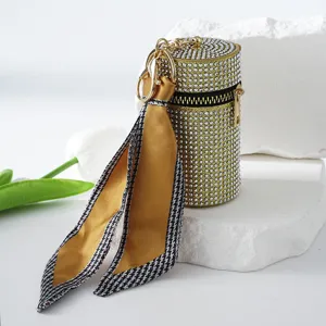 Close-up of a luxurious rhinestone-studded lipstick bag keychain with silk scarf charm
