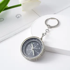 Close-up of a stylish rhinestone-studded mini compass keychain for outdoor navigation
