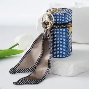 Close-up of a blue rhinestone lipstick holder keychain with an elegant silk scarf detail.
