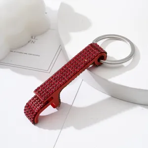 Close-up detail of a red rhinestone-encrusted bottle opener keychain with a silver ring