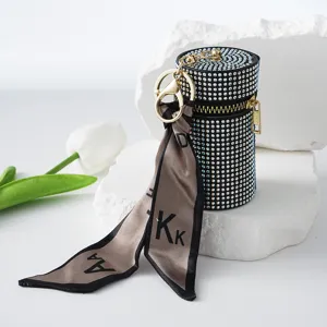 Detailed view of a luxury rhinestone lipstick bag with an elegant silk scarf keychain.