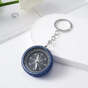 Close-up of mini outdoor compass keychain with blue rhinestone rim and aluminum dial