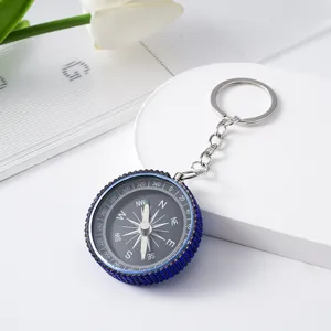 Detailed view of a mini outdoor compass keychain with blue rhinestone-encrusted rim