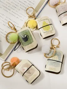 Mini PU leather notebook keychain with cute pom-pom and metal clasp for bag decor.