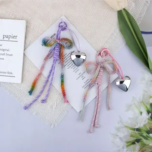 Detail view of woven cotton rope bow bag charms with shiny silver heart pendants.