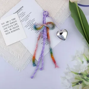 Detail of cotton rope bow keychain with a silver heart charm on white aesthetic background