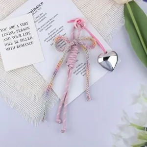 Close-up of a pastel braided rope bow keychain with a glossy silver heart charm