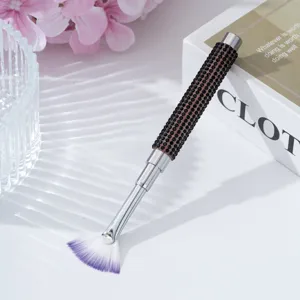 Detail view of a professional fan-shaped nail art brush with rhinestone handle
