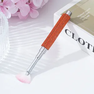 Detail view of nail art fan brush with orange rhinestone handle and pink bristles
