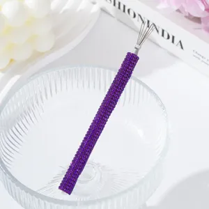 Close-up of purple rhinestone-encrusted nail art drawing tool on a elegant glass bowl