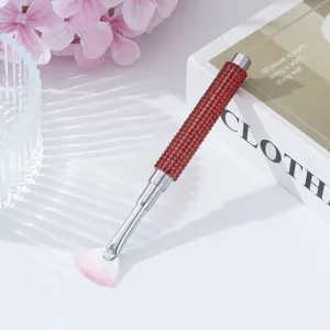 Close-up view of red rhinestone handle nail fan brush with pink gradient bristles