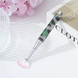 Elegant nail art fan brush with sparkling green rhinestone handle and soft pink-tipped bristles.