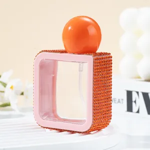 Detailed macro view of square 40ml spray bottle decorated with orange rhinestones