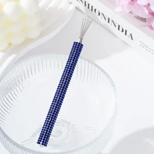 Close-up detail of a blue rhinestone encrusted nail art wire drawing tool in a bowl