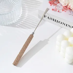 Detail of stainless steel nail art spatula with rhinestone handle on white surface