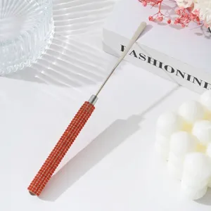 Close-up detail of stainless steel nail art mixing stick with vibrant orange rhinestone handle