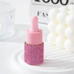 Detailed macro view of a pink rhinestone-covered essential oil dropper bottle for travel