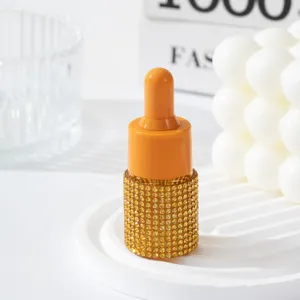 Macro view of an orange essential oil bottle with yellow rhinestone-encrusted texture.