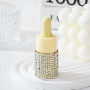 Close-up detail of a luxury rhinestone-studded dropper bottle on a white tiered display.