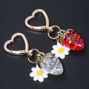 Detailed shot of translucent strawberry and daisy keychains with heart clasps.