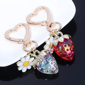 Macro view of translucent strawberry charms with rhinestones and white daisy flower.