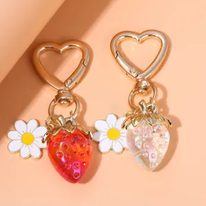 Close-up of translucent red and iridescent strawberry charms with daisy and heart clasps